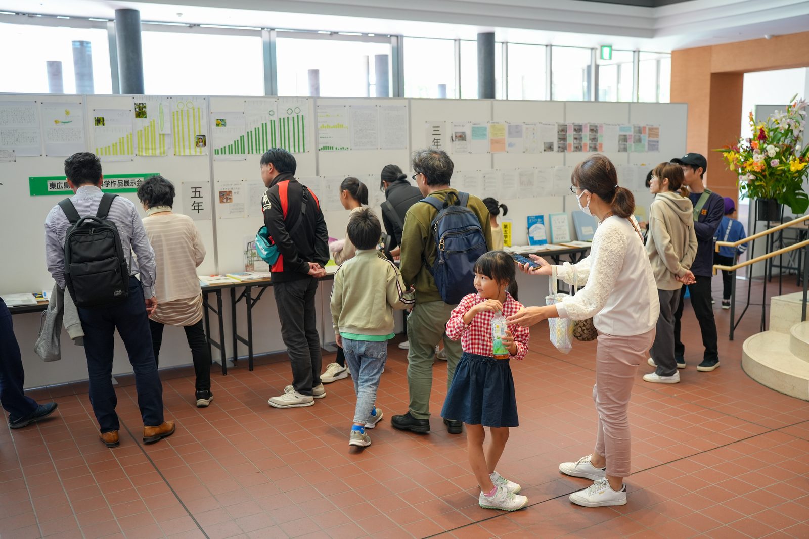 ロビーに並んだ展示パネルを、親子連れなど大勢の来場者が見て回る様子